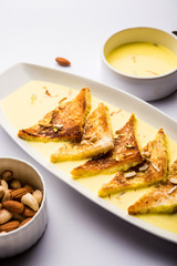 shahi tukra/tukda or Double ka meetha is a bread pudding Indian sweet of fried bread slices soaked in rabid or sweet saffron milk garnished with dry fruits, selective focus