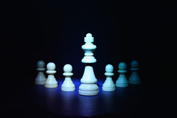 Wooden chess figures under dark and dramatic lighting