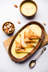 shahi tukra/tukda or Double ka meetha is a bread pudding Indian sweet of fried bread slices soaked in rabid or sweet saffron milk garnished with dry fruits, selective focus