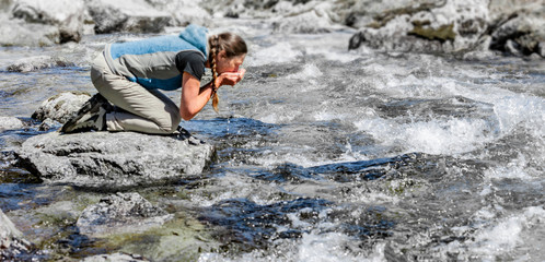 Frau beim Wasser trinken aus einem Bergbach