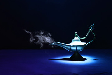Image of magical mysterious aladdin lamp with smoke. Dark background and dramatic light