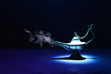 Image of magical mysterious aladdin lamp with smoke. Dark background and dramatic light