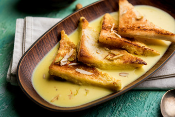 shahi tukra/tukda or Double ka meetha is a bread pudding Indian sweet of fried bread slices soaked in rabid or sweet saffron milk garnished with dry fruits, selective focus