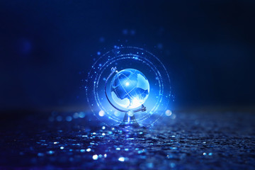 Small crystal globe in front of dark and dramatic light.global issues concept