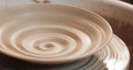 An empty plate with relief rotates on the pottery wheel, close up. Winding clay structure....