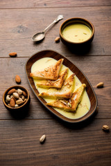 shahi tukra/tukda or Double ka meetha is a bread pudding Indian sweet of fried bread slices soaked in rabid or sweet saffron milk garnished with dry fruits, selective focus