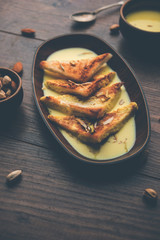 shahi tukra/tukda or Double ka meetha is a bread pudding Indian sweet of fried bread slices soaked in rabid or sweet saffron milk garnished with dry fruits, selective focus