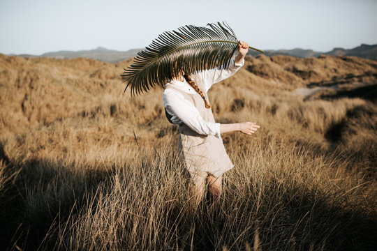 Girl holding palm branch in grassland