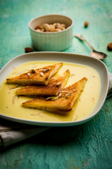shahi tukra/tukda or Double ka meetha is a bread pudding Indian sweet of fried bread slices soaked in rabid or sweet saffron milk garnished with dry fruits, selective focus