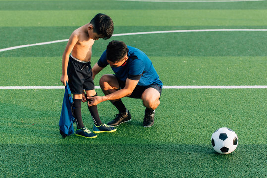 Father helping son dressing up in soccer uniform