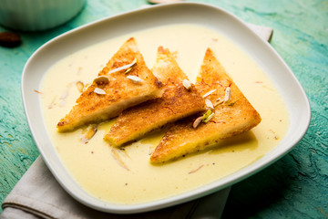 shahi tukra/tukda or Double ka meetha is a bread pudding Indian sweet of fried bread slices soaked in rabid or sweet saffron milk garnished with dry fruits, selective focus