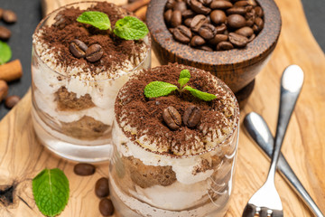 Classic tiramisu dessert in a glass on dark concrete background