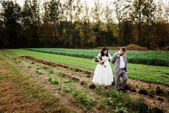 bride and groom walking in cabbage fiel at sunset