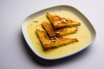 shahi tukra/tukda or Double ka meetha is a bread pudding Indian sweet of fried bread slices soaked in rabid or sweet saffron milk garnished with dry fruits, selective focus
