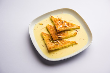 shahi tukra/tukda or Double ka meetha is a bread pudding Indian sweet of fried bread slices soaked in rabid or sweet saffron milk garnished with dry fruits, selective focus