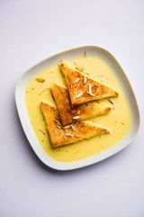 shahi tukra/tukda or Double ka meetha is a bread pudding Indian sweet of fried bread slices soaked in rabid or sweet saffron milk garnished with dry fruits, selective focus