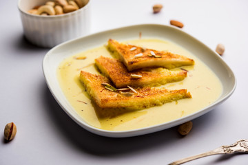 shahi tukra/tukda or Double ka meetha is a bread pudding Indian sweet of fried bread slices soaked in rabid or sweet saffron milk garnished with dry fruits, selective focus