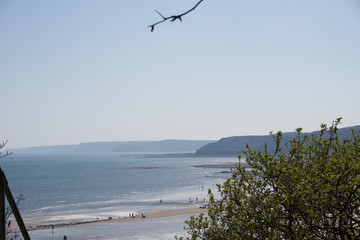 View out to sea across beach from cliff tops in Scarborough, UK on a clear blue sky sunny da