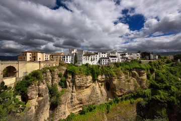 Fototapeta premium Sun on white buildings and orange cliffs at El Tajo Gorge Ronda Spain