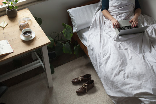 Woman is working on a laptop in her bed