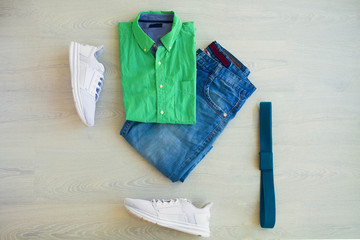 Green plaid shirt, jeans shorts and white sneakers on a white background, men's wear. Top view.