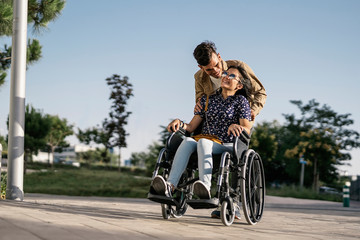Young woman sitting on a wheelchair and her boyfriend walking