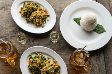 traditional Balinese food called lawar. Lawar is minced meat mixed with vegetables, long beans and spices then stirred evenly. Eat using rice and freash iced tea. Served on a wooden table