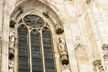 Ornate carvings around a stained glass window at the Duomo Milano (Milan Cathedral)
