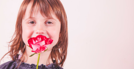 Gender identity development in early childhood concept. Beautiful little child girl holding rose in her mouth.