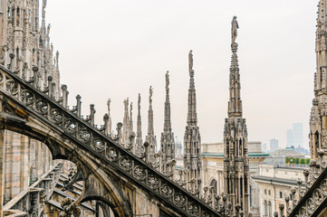 Fototapeta na wymiar Flying buttress and ornately carved stonework on the roof of the Duomo Milano (Milan Cathedral), Italy