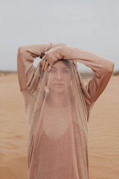 Woman hiding her face with clothes in desrtt