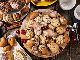 Oatmeal cookies and sand chocolate cake with cherry berry and crispy wafer rolls with cream on cutting board on wooden table in rustic style. Limitations for diabetics. Traditional sweets.
