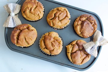 Tasty muffins on the baking sheet on the white table