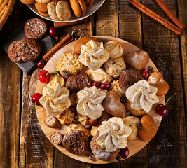 Oatmeal cookies and sand chocolate cake with cherry berry and crispy wafer rolls with cream on cutting board on wooden table in rustic style. Limitations for diabetics. Yummy.