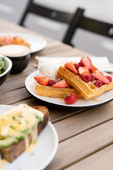 Delicious breakfast in the summer cafe. On a wooden table, a dessert of Viennese waffles with a scoop of ice cream and fruit berries of strawberry and raspberry. 