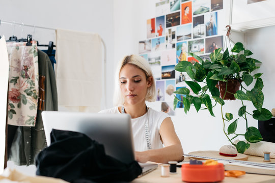 Young tailor browsing laptop in workshop