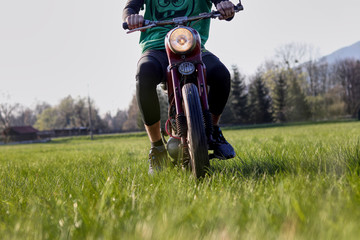 Youth is driving veteran jawa motorbike in the field and grass. Main light lighting in all directions. Lover of motorbikes tries renovated  pioneer, fechtl. Pincek. Fichtl. Man has a green t-shirt - obrazy, fototapety, plakaty