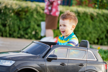 joy small boy is driving toy car on the playground  