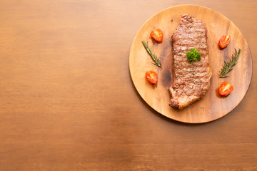 Fresh cooked sirloin beef steak with cherry tomato and rosemary on top with parsley, Wood background, Copy space on the left
