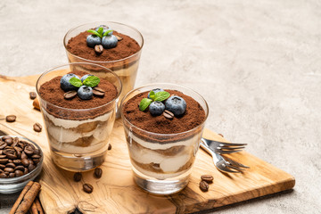 Classic tiramisu dessert in a glass with blueberries on concrete background