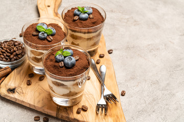 Classic tiramisu dessert in a glass with blueberries on concrete background