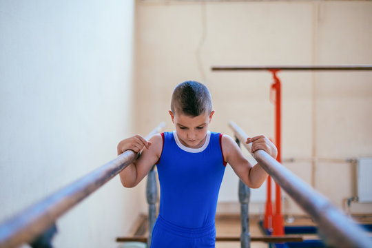Gymnastics, young boy practicing on parallel bars