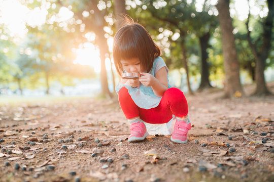 Asian little girl playing with a magnifying glass