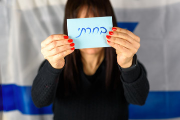 Young Woman Holding Ballot Front Of Face on Israeli Flag Background.Hebrew text I Voted on voting paper. Israel to hold new elections 17 September 2019 after Netanyahu coalition talks fail.