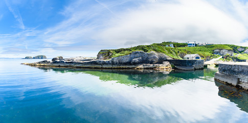 Ballintoy Old Harbour and coastal rocks with a very calm sea and blue sky, Northern Ireland