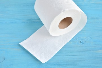 Roll of white toilet paper with selective focus on blue wooden background. Clean soft toilet paper for daily personal hygiene. Recycle paper towel on blue textured backdrop. Toilet rolls