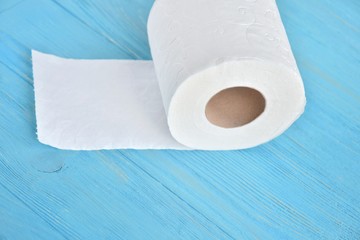 Roll of white toilet paper with selective focus on blue wooden background. Clean soft toilet paper for daily personal hygiene. Recycle paper towel on blue textured backdrop. Toilet rolls