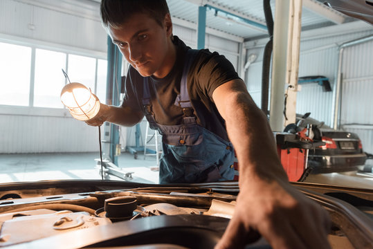 Workman exploring engine in garage