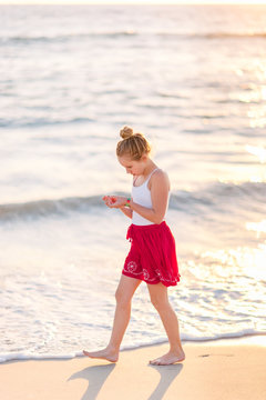 Girl collecting shells at the beach at sunset