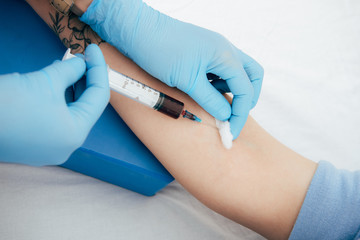 cropped view of donor and doctor with syringe obtaining blood sample